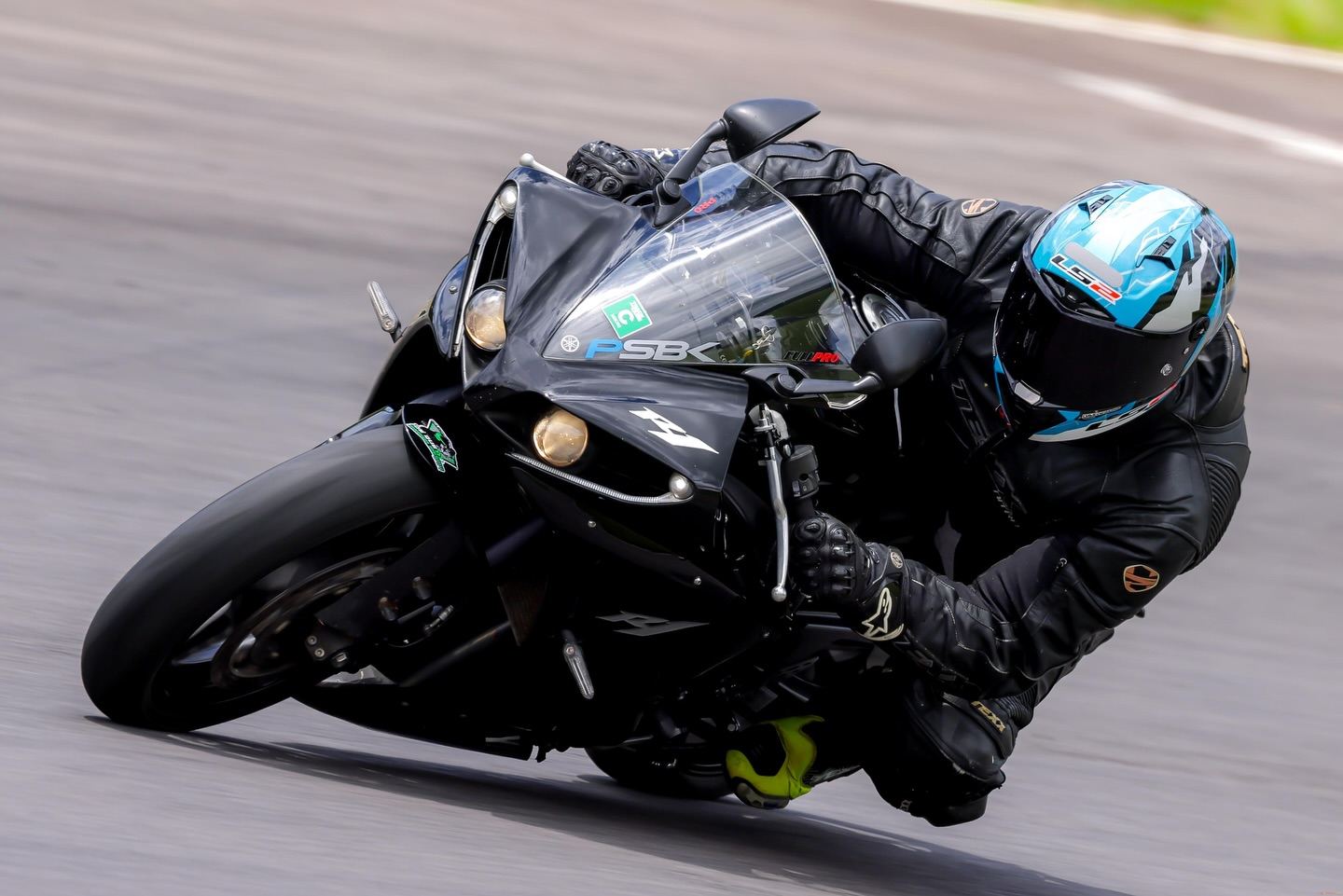 Piloto do grupo deitado na curva com moto preta